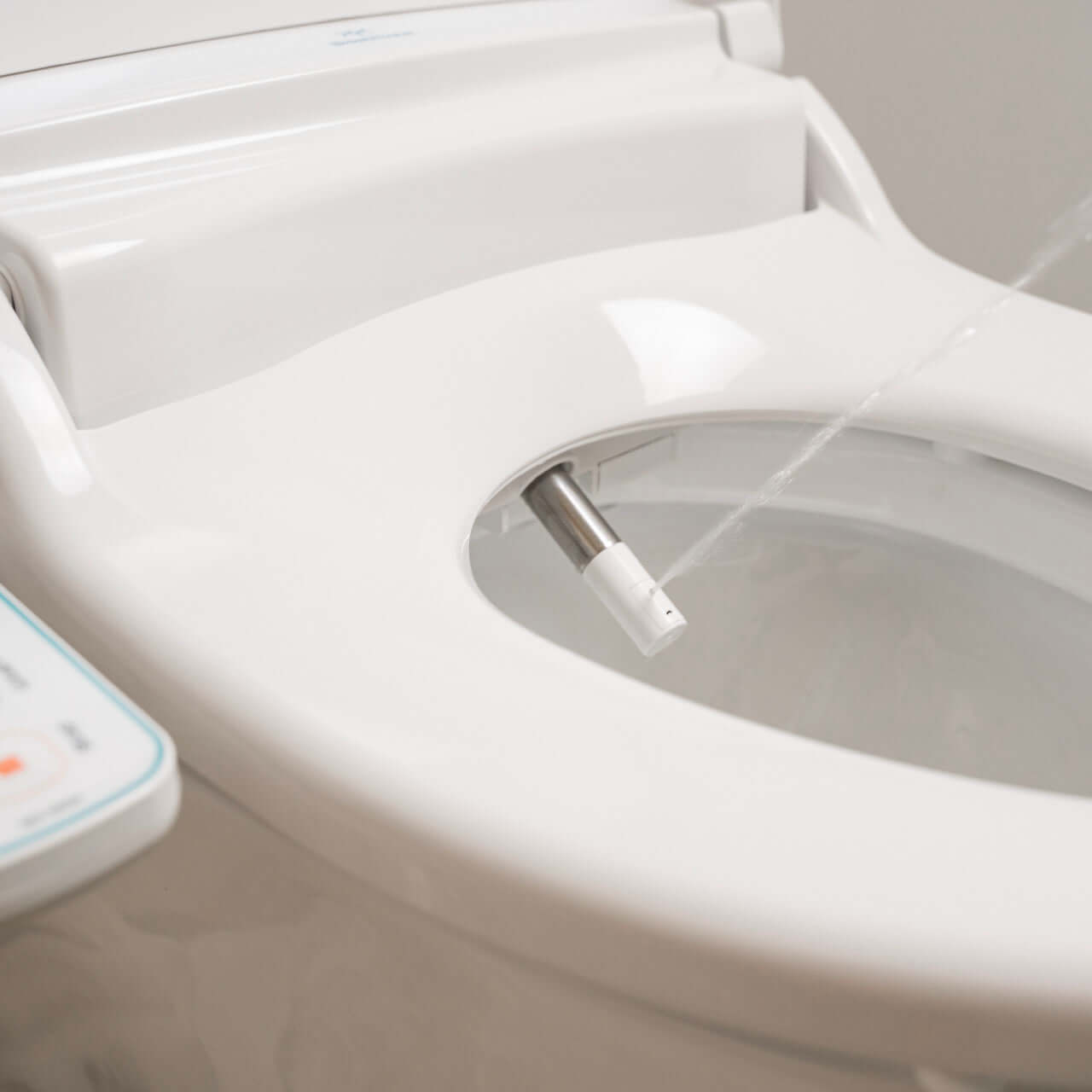 Close-up of BidetMate 1000 Series bidet nozzle spraying water for hygienic cleansing.