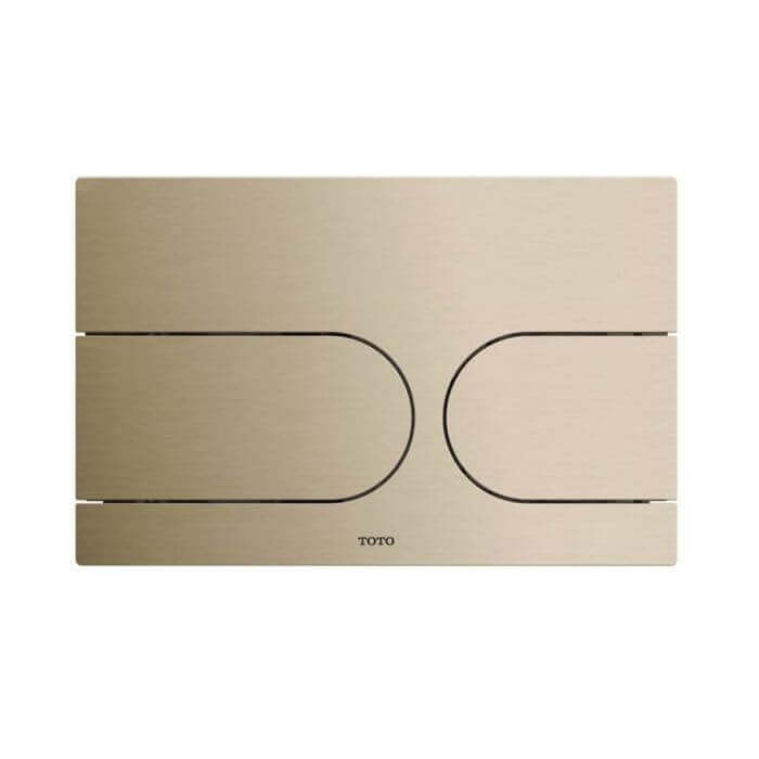 Gold toilet flush plate with TOTO branding on a white background