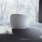 White cylindrical object on a reflective surface with a snowy landscape in the background