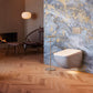 Modern bathroom with a toilet against a textured wall, wooden floor, and fireplace.