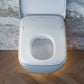 Wall mounted toilet with nightlight shining on floor underneath with lid open