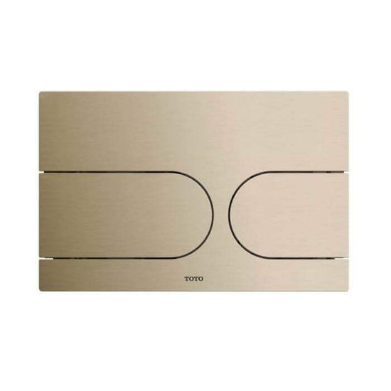 Gold toilet flush plate with TOTO branding on a white background